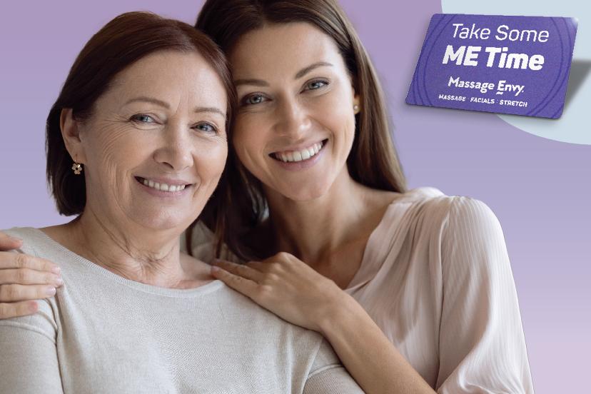Daughter placing her arms around her mother as they both smile.