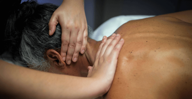 Therapist massaging woman's neck at Massage Envy clinic. 