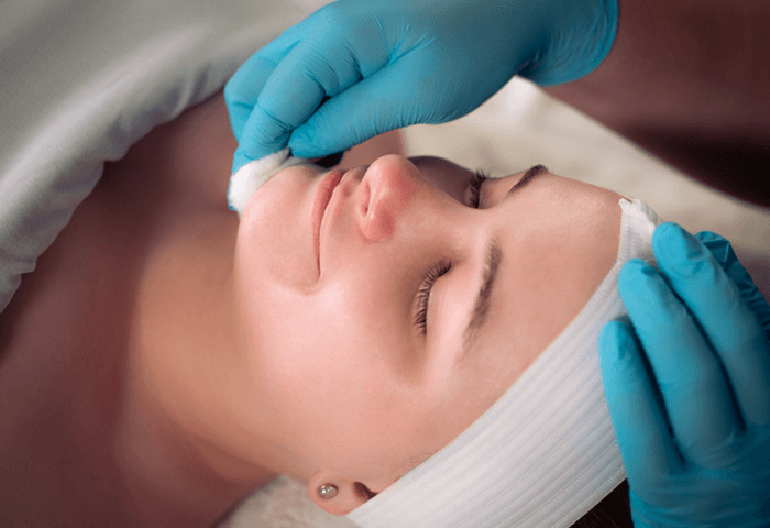 Close-up of woman smiling as she receives a facial from a Massage Envy esthetician. 