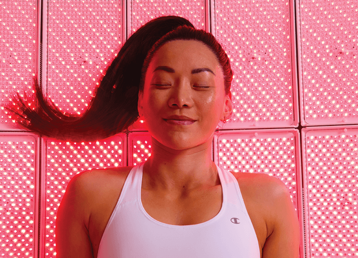 Woman smiling and relaxing during Full Body LED Light therapy session. 