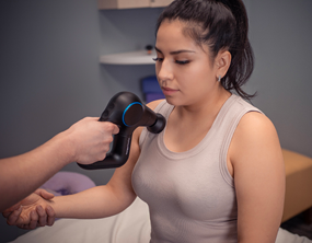 Woman receiving rapid tension relief therapy along her front shoulder.