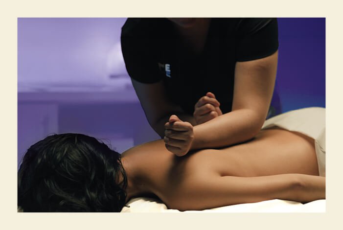 Woman laying on table as a therapist reaches down to massage her back. 